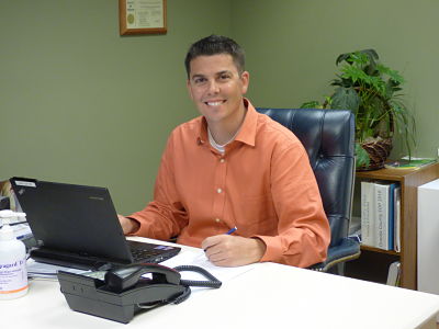 This is a picture of a person smiling while writing something down from a laptop