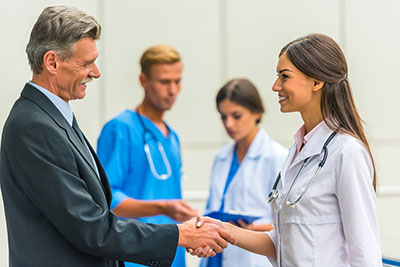 This is a picture of a interviewee shaking the hand of a doctor while a doctor and nurse stand in the background